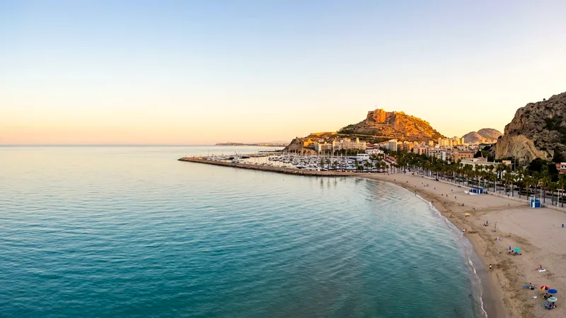 Postiguet Beach and Santa Bárbara Castle on its hill above Alicante at golden hour.